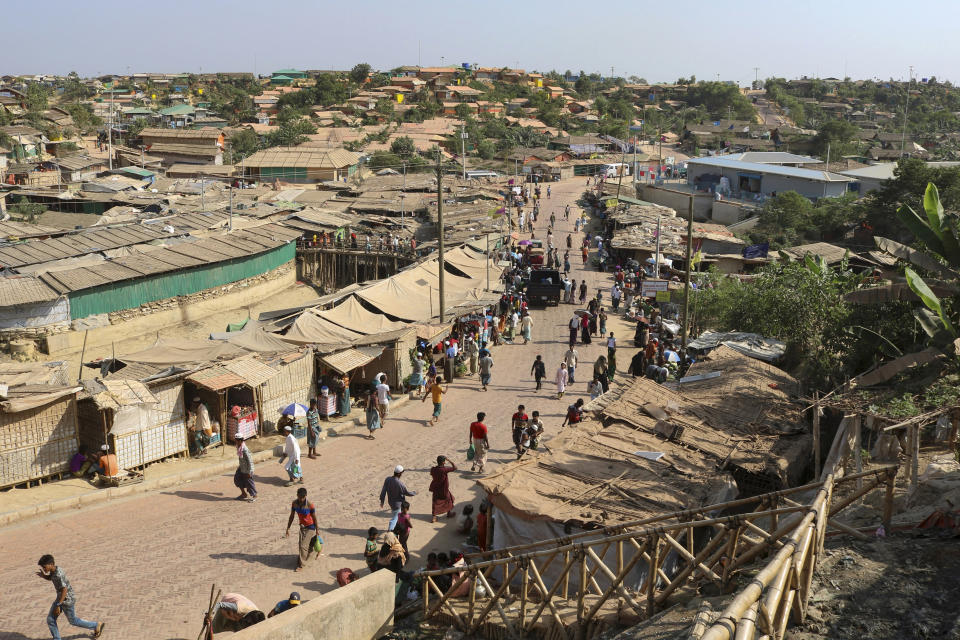 CORRECTS DATE - FILE - In this April 12, 2020, file photo, Rohingya refugees walk through one of the arterial roads at the Kutupalong refugee camp in Cox's Bazar, Bangladesh. Authorities on Thursday, May 14, 2020 reported the first coronavirus case in the crowded camps for Rohingya refugees in southern Bangladesh, where more than 1 million refugees have been sheltered, a Bangladeshi official and the United Nations said. (AP Photo/Shafiqur Rahman, File)