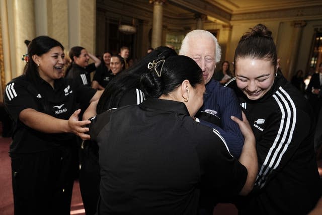 Charles being hugged by players from the New Zealand women's rugby team