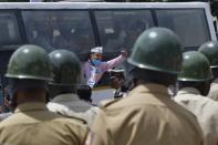 Police personnel stand guard as an activist from a farmers rights organisation gestures during a protest following the recent passing of agriculture bills in the Lok Sabha (lower house), in Bangalore on September 25, 2020. - Angry farmers took to the streets and blocked roads and railways across India on September 25, intensifying protests over major new farming legislation they say will benefit only big corporates. (Photo by Manjunath Kiran / AFP) (Photo by MANJUNATH KIRAN/AFP via Getty Images)