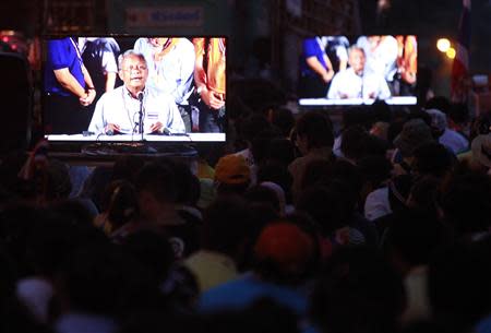 Anti-government protesters watch a television broadcast of a speech by protest leader Suthep Thaugsuban during a rally outside the Government House in Bangkok December 9, 2013. REUTERS/Chaiwat Subprasom