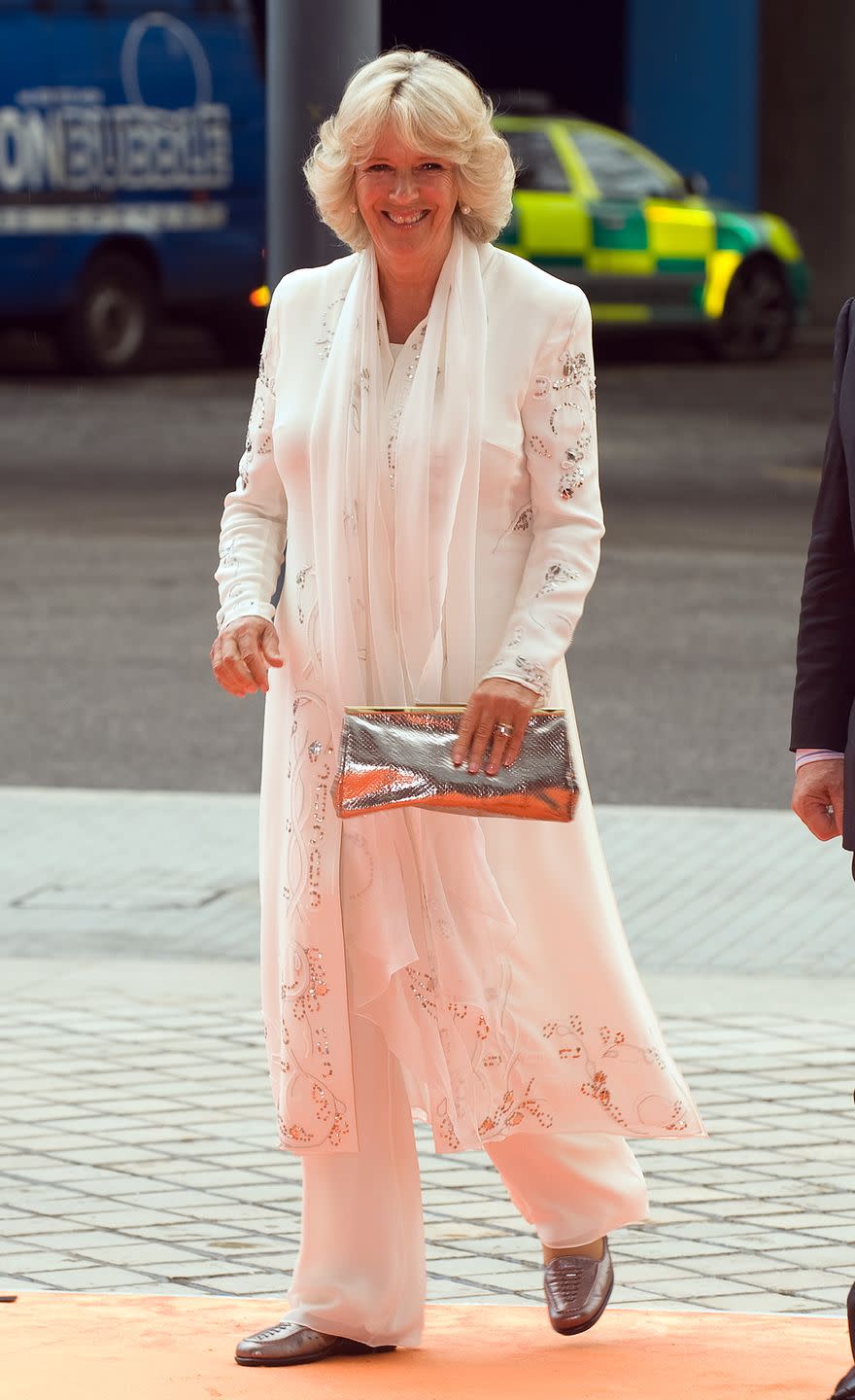 <p>On a day out in London, Camilla looked breezy in this flowing white coatdress with floral embroidery and matching white trousers. </p>