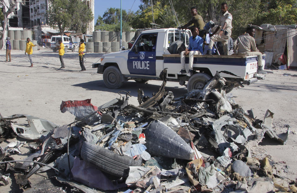 A police vehicle drives past wreckage after a suicide car bomb attack on a government building in the capital Mogadishu, Somalia, Saturday, March 23, 2019. Al-Shabab gunmen stormed the government building after a suicide car bombing, killing at least five people including the country's deputy labor minister, police said, in the latest attack by Islamic extremist fighters in the Horn of Africa nation. (AP Photo/Farah Abdi Warsameh)