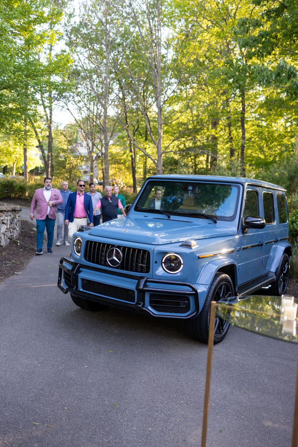a group of people standing next to a blue car