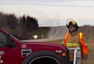 Firefighters block the highway near Gainford, Alberta, as emergency crews battle a fire at the scene where 13 cars - four carrying petroleum crude oil and nine carrying liquefied petroleum gas - came off the tracks in an early-morning derailment on Saturday, October 19, 2013. THE CANADIAN PRESS/Jason Franson