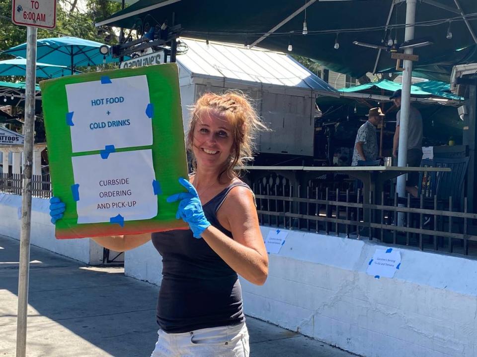 Molly Smith wears protective gloves while advertising a restaurant’s curbside pickup on Duval Street in Key West on March 23, 2020.