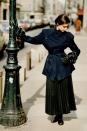 <p>A model wears a belted jacket and pleated skirt by Yohji Yamamoto.</p>