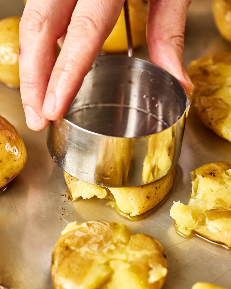 The bottom of a measuring cup is used to smash potatoes