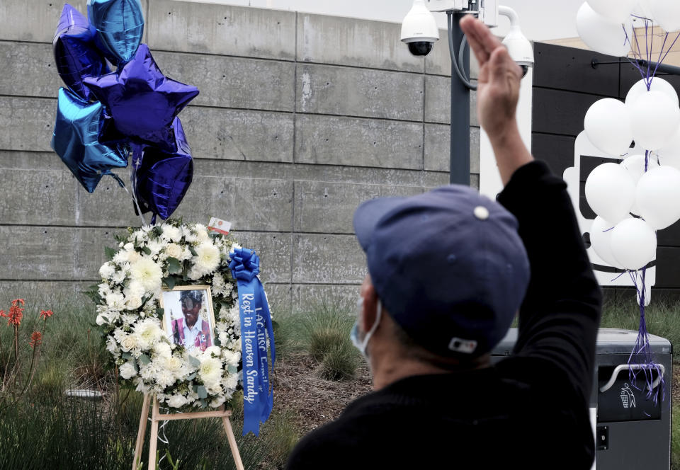 A passerby offers a prayer at a memorial at the bus stop on Wednesday, Jan. 19, 2022. in downtown Los Angeles where nurse Sandra Shells had been attacked on Thursday, Jan. 13, 2022. Shells, a 70-year-old nurse, was on her way to work at LA County-USC Medical Center when she was allegedly stabbed, fell backward and hit her head on the ground. She died Sunday, Jan. 16, 2022 at a hospital. (AP Photo/Richard Vogel)