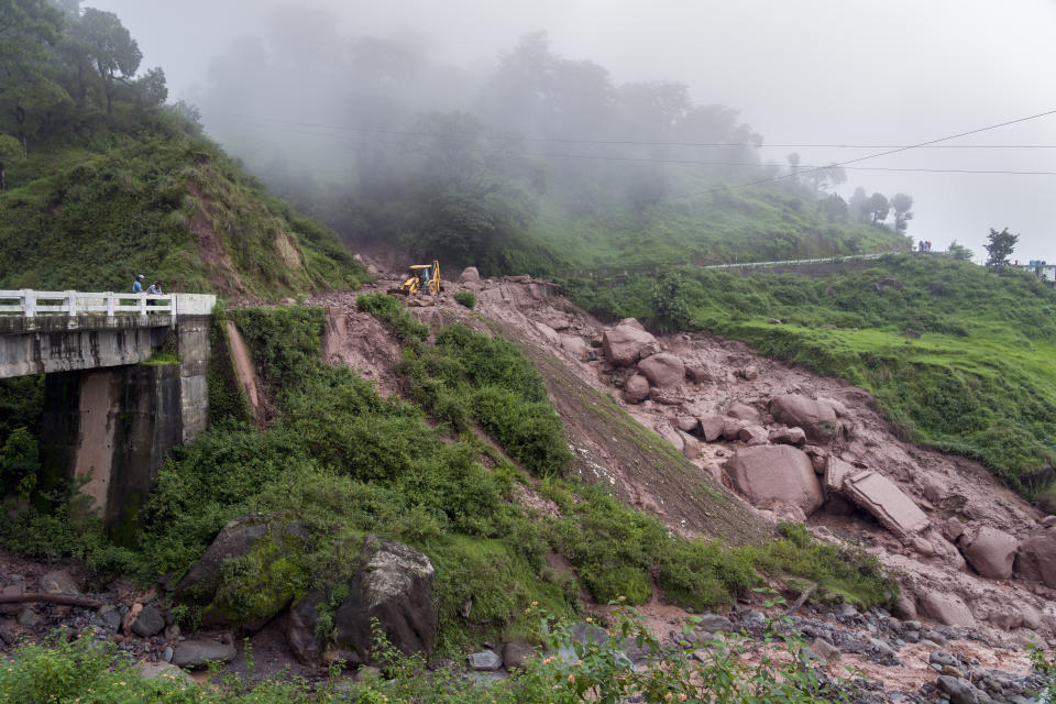 An earth-mover is used to remove the debris after a landslide damaged part of a road near Dharamshala, India, Monday, Aug. 14, 2023. Heavy monsoon rains triggered floods and landslides in India's Himalayan region, leaving several people dead and many others trapped. (AP Photo/Ashwini Bhatia)