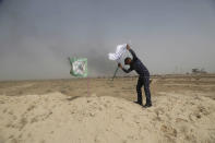 <p>A policeman places an Iraqi federal police flag next to a Shiite Popular Mobilization Forces flag during a fight against Islamic State militants outside Fallujah, Iraq, May 28, 2016. Days into an Iraqi military operation to push Islamic State fighters out of Fallujah, residents still inside the city are preparing for a long battle, with some saying they fear being trapped between two forces they don’t fully trust.(AP Photo/Khalid Mohammed) </p>