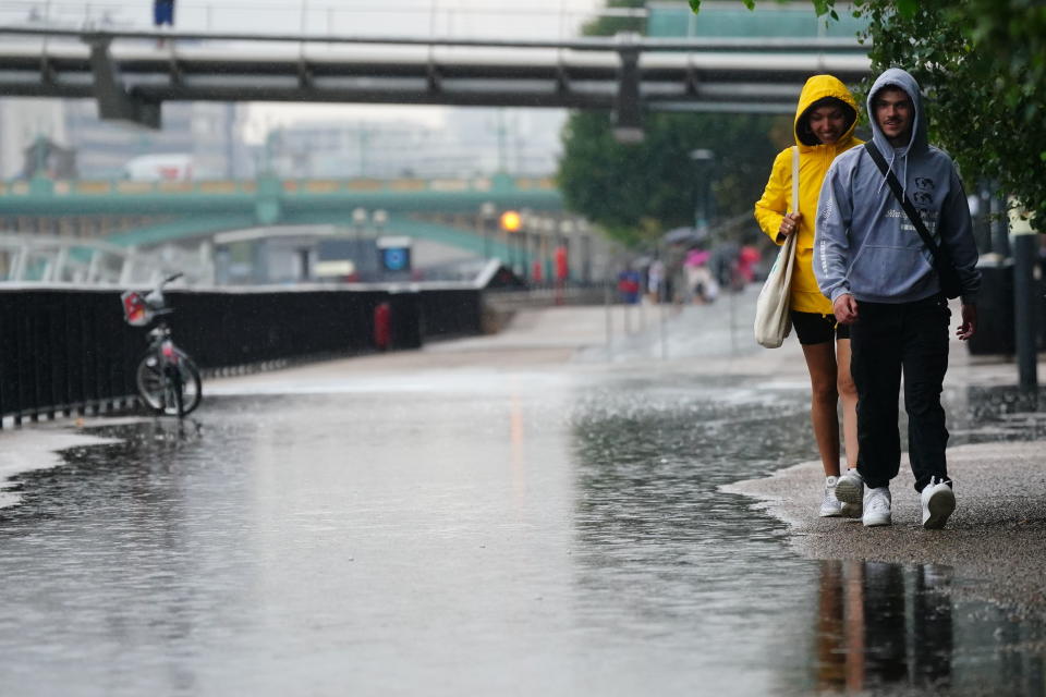 People walk in the rain in London, Wednesday Aug. 17, 2022.. After weeks of sweltering weather, which has caused drought and left land parched, the Met Office's yellow thunderstorm warning forecasts torrential rain and thunderstorms that could hit parts England and Wales. (Victoria Jones/PA via AP)