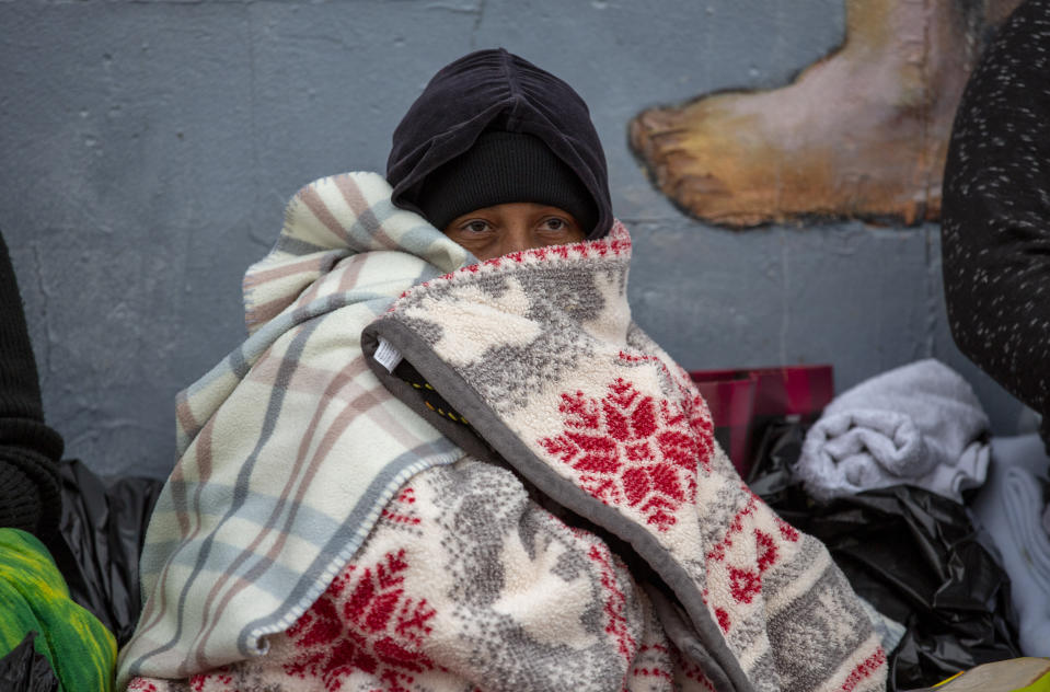 A migrant covers himself with blankets while waiting for help in downtown El Paso, Texas, Sunday, Dec. 18, 2022. Texas border cities were preparing Sunday for a surge of as many as 5,000 new migrants a day across the U.S.-Mexico border as pandemic-era immigration restrictions expire this week, setting in motion plans for providing emergency housing, food and other essentials. (AP Photo/Andres Leighton)