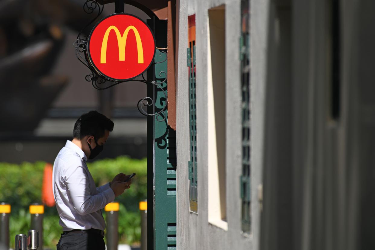 A man wearing face mask as a preventive measure against the spread of the COVID-19 coronavirus waits outside a McDonald's fast food outlet at Boat Quay next to the Raffles Place financial business district in Singapore on April 14, 2020. (Photo by ROSLAN RAHMAN / AFP) (Photo by ROSLAN RAHMAN/AFP via Getty Images)