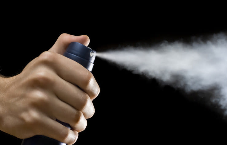 deodorant being sprayed on a dark background