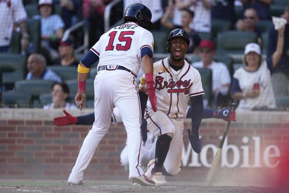 Atlanta Braves' Ozzie Albies (1) and Nicky Lopez (15) react after scoring on a two-run base hit by Michael Harris II in the seventh inning of a baseball game against the Washington Nationals, Sunday, Oct. 1, 2023, in Atlanta. (AP Photo/John Bazemore)