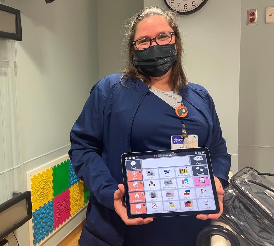 Misti Martin, a Shore Pediatric Care Center nurse, is pictured with a few of the tools in Shore's sensory-friendly toolbox, including a tactile wall behind her, an iPad app for communicating with nonverbal children, a weighted blanket, and a remote-control bubble wall.