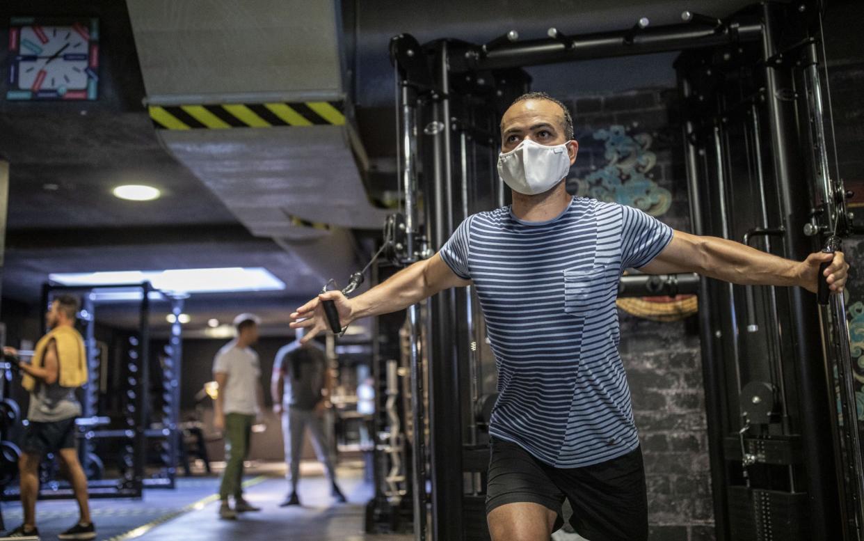 Man performs exercise while wearing facemask in gym - GETTY IMAGES