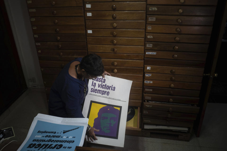 Sara Vega, especialista de la Cinemateca cubana, muestra un poster promocional de una película durante una entrevista en la Cinemateca en La Habana, el martes 11 de julio de 2023. El listado de Memoria del Mundo de la UNESCO ahora incluye una colección de seis décadas de carteles impresos en serigrafía de películas cubanas. (AP Foto/Ramón Espinosa)