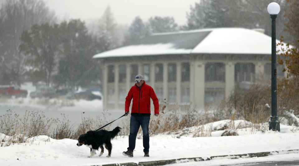 A man walks his dog around Washington Park as an autumn snowstorm sweeps over the intermountain West, Tuesday, Oct. 29, 2019, in Denver. Forecasters predict that this second storm in two days will bring up to a foot of snow in some places in the region as well as pack an intense cold that may drop temperatures to possibly record-setting lows. (AP Photo/David Zalubowski)