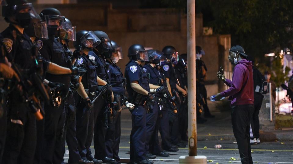 Ein Demonstrant steht während einer Demonstration vor Polizisten in Rochester. Nachdem ein 41-jähriger Afroamerikaner infolge eines brutalen Polizeieinsatzes verstarb, wurden sieben Beamte vom Dienst suspendiert.