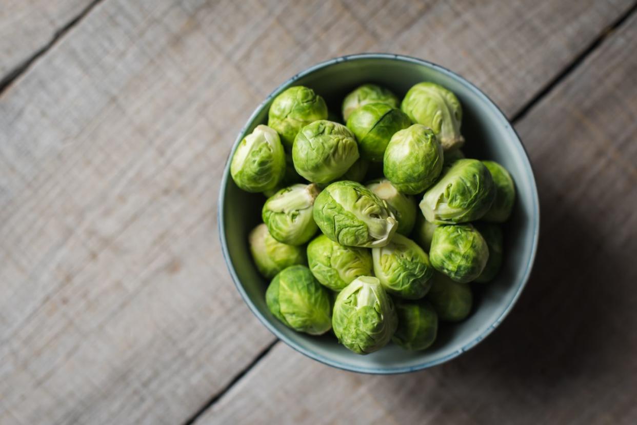 overhead view of bowl of brussels sprouts on wooden background