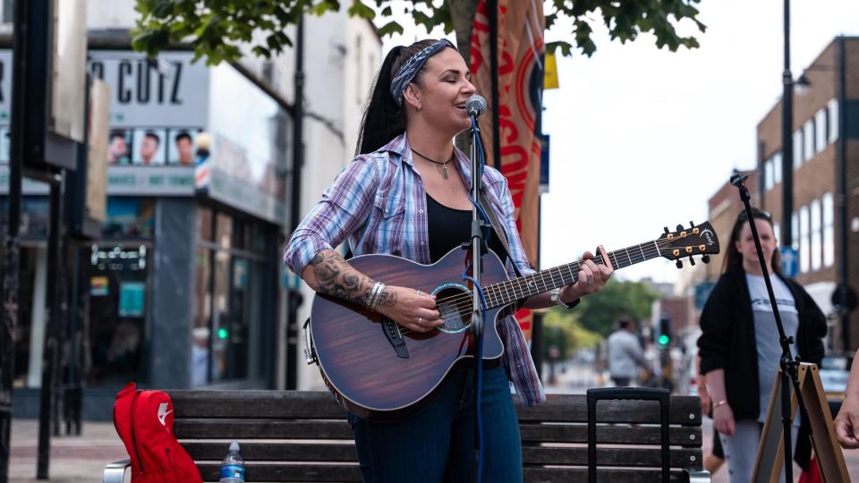 A performer playing a guitar on Make Music Day