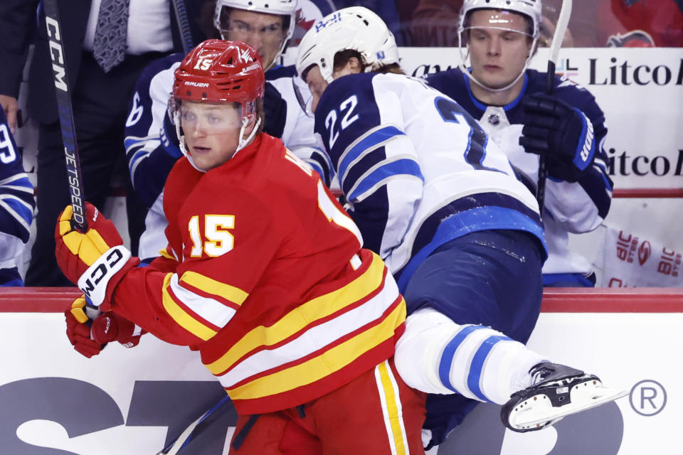 Winnipeg Jets' Mason Appleton (22) is checked into the Jets bench by Calgary Flames' Dryden Hunt during the second period of an NHL hockey game in Calgary, Alberta, Monday, Feb. 19, 2024. (Larry MacDougal/The Canadian Press via AP)