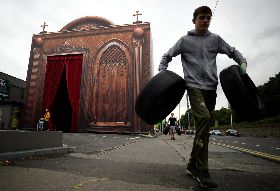 <p>Vor einer Beichtstuhl-Kulisse räumt ein Junge in Dublin zwei Reifen weg. In der irischen Hauptstadt finden vor dem Besuch von Papst Franziskus beim Weltfamilientreffen letzte Vorbereitungen statt. (Bild: Reuters/Clodagh Kilcoyne) </p>