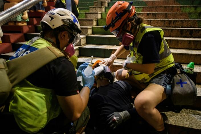 Medics carry saline solution to flush the eyes of protesters affected by tear gas or pepper spray (AFP Photo/ANTHONY WALLACE)