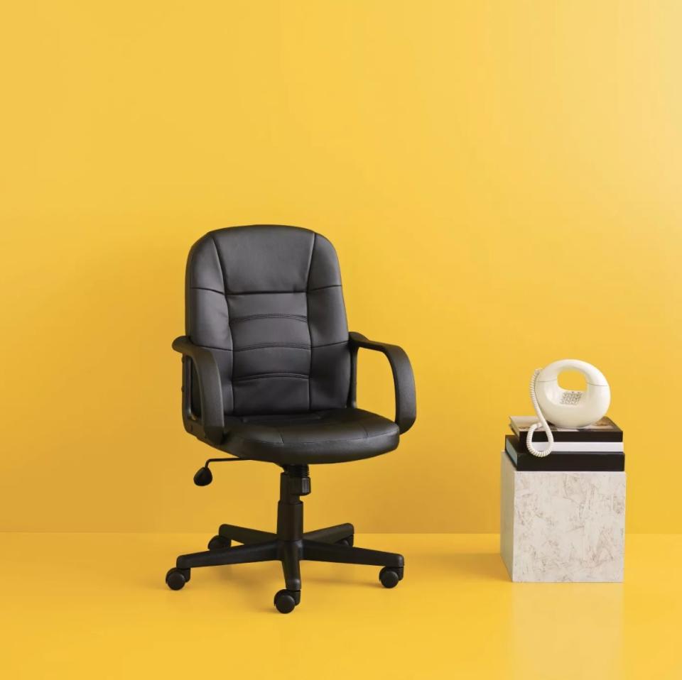 The black leather office chair on a yellow backdrop