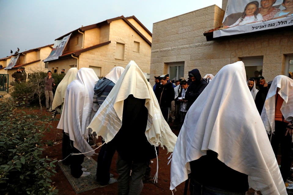 Pro-settlement activists pray outside houses that about to be evacuated in the settlement of Ofra in the occupied West Bank, during an operation by Israeli forces to evict the houses