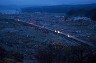 In this March 15, 2011, file photo, vehicles pass through the ruins of the leveled city of Minamisanriku, Miyagi Prefecture, northeastern Japan, four days after the Tsunami devastated the area. (AP Photo/David Guttenfelder, File)