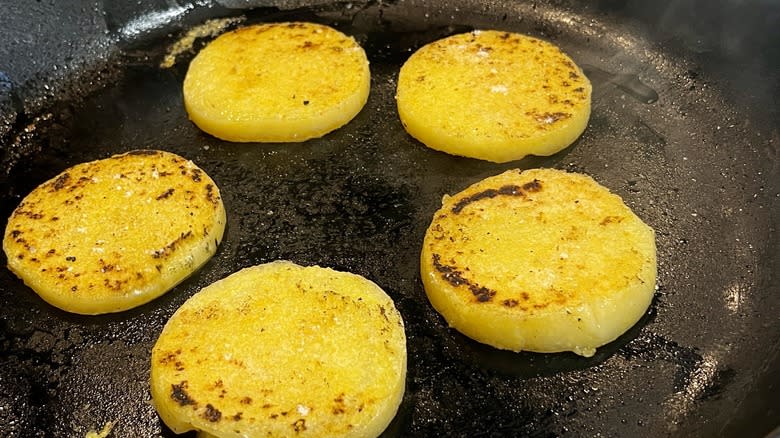 polenta rounds frying in a cast-iron skillet