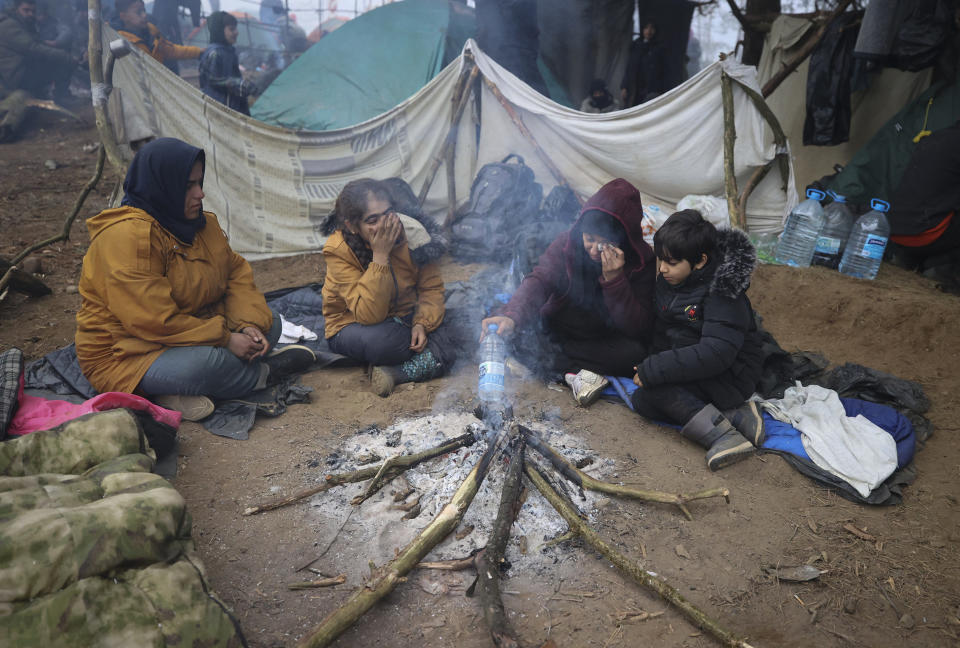 Migrants from the Middle East and elsewhere warm up at the fire gathering at the Belarus-Poland border near Grodno, Belarus, Thursday, Nov. 11, 2021. The European Union has accused Belarus' authoritarian President Alexander Lukashenko of encouraging illegal border crossings as a "hybrid attack" to retaliate against EU sanctions on his government for its crackdown on internal dissent after Lukashenko's disputed 2020 reelection. (Leonid Shcheglov/BelTA via AP)