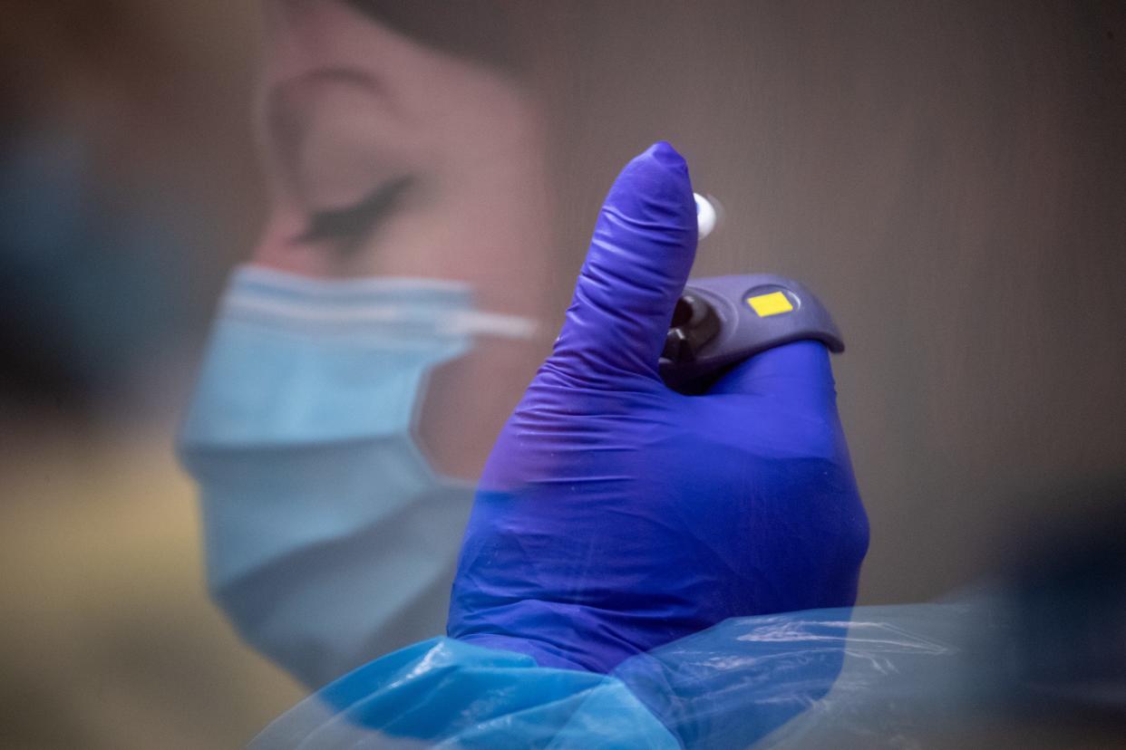 Rebekah Dowling processes COVID-19 test samples under a hood in a microbiology lab, Oct. 4, 2021, at TGen North in Flagstaff, Arizona.