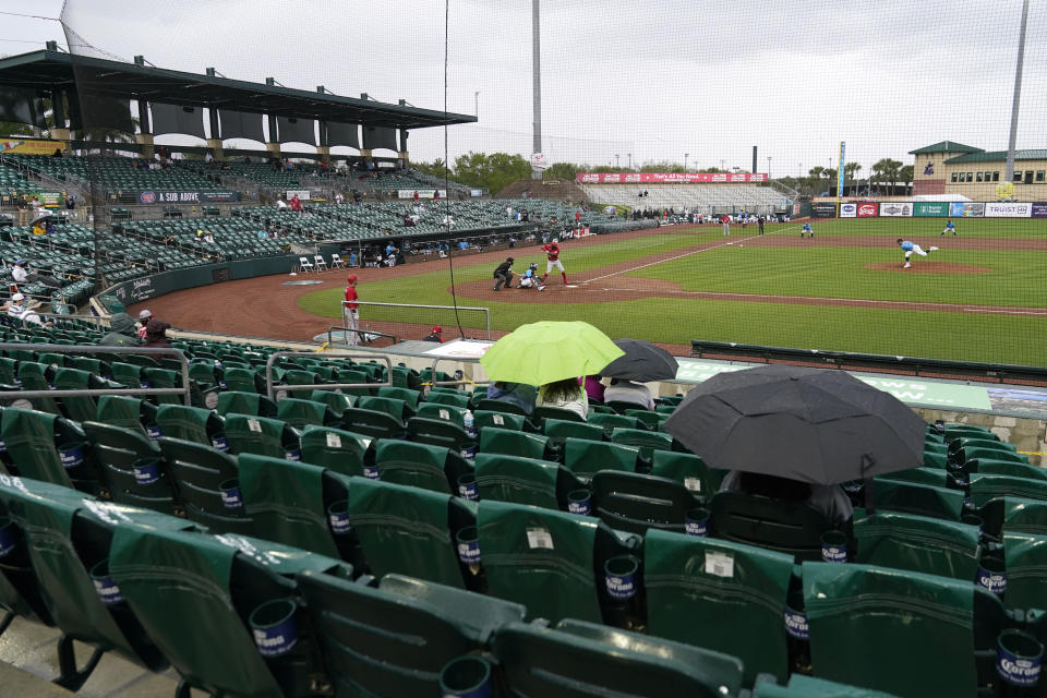 Fans sit in the rain at Roger Dean Stadium during a spring training baseball game between the Miami Marlins and Washington Nationals, Saturday, March 6, 2021, in Jupiter, Fla. (AP Photo/Lynne Sladky)