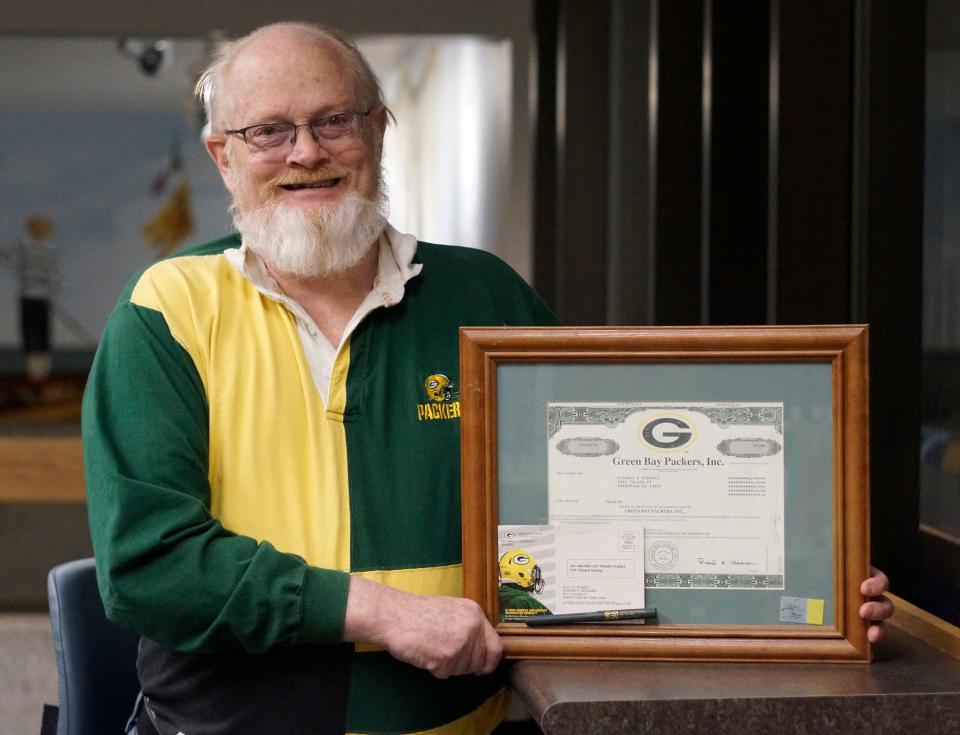 Green Bay Packer Fan Richard Burgard, of Sheboygan, poses with his framed Green Bay Packer stock certificate, Thursday, January 20, 2022, in Sheboygan, Wis. 