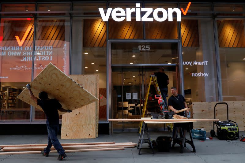 Workers board up a Verizon store in midtown Manhattan during protests against the death in Minneapolis police custody of George Floyd, in New York