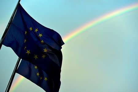 A rainbow is seen behind European flags during a euro zone EU leaders emergency summit on the situation in Greece at the European Council headquarters in Brussels, Belgium, July 7, 2015. REUTERS/Eric Vidal