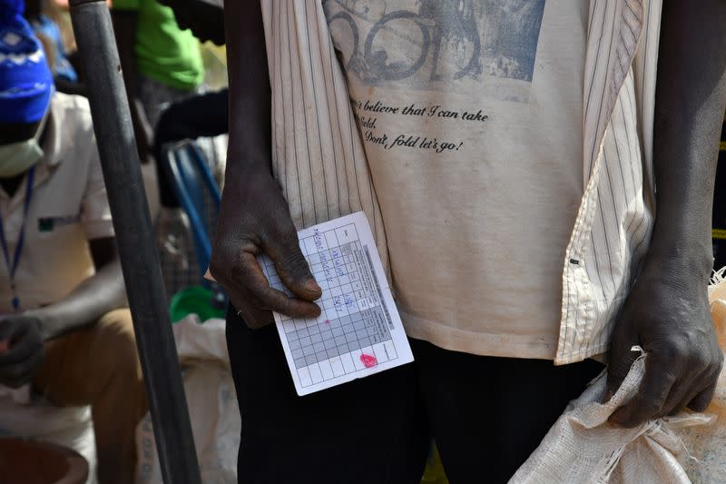 A displaced man, who fled from attacks of armed militants in town of Roffenega, holds a card showing the quantities of food he will receive from the World Food Programme (WFP) in Pissila