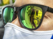 Health workers collecting a nasal swab from a woman are reflected on the sunglasses in Rayong province, Thailand, Tuesday, July 14, 2020. Authorities set up testing for anyone concerned they might have come into contact with an Egyptian soldier who visited a shopping mall in Rayong last week and then tested positive for COVID-19. In Thailand, where there has been no reports of locally transmitted cases for seven weeks, health authorities were rushing to trace the contacts of two recent foreign arrivals in the country who were infected with the coronavirus and may have violated quarantine rules.(AP Photo/Sakchai Lalit)