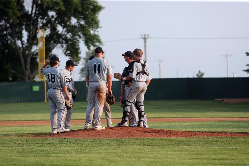 Members of the Aberdeen Smittys and coach Brandon Kusler meet on the mound during a game against Redfield on Monday in Redfield.