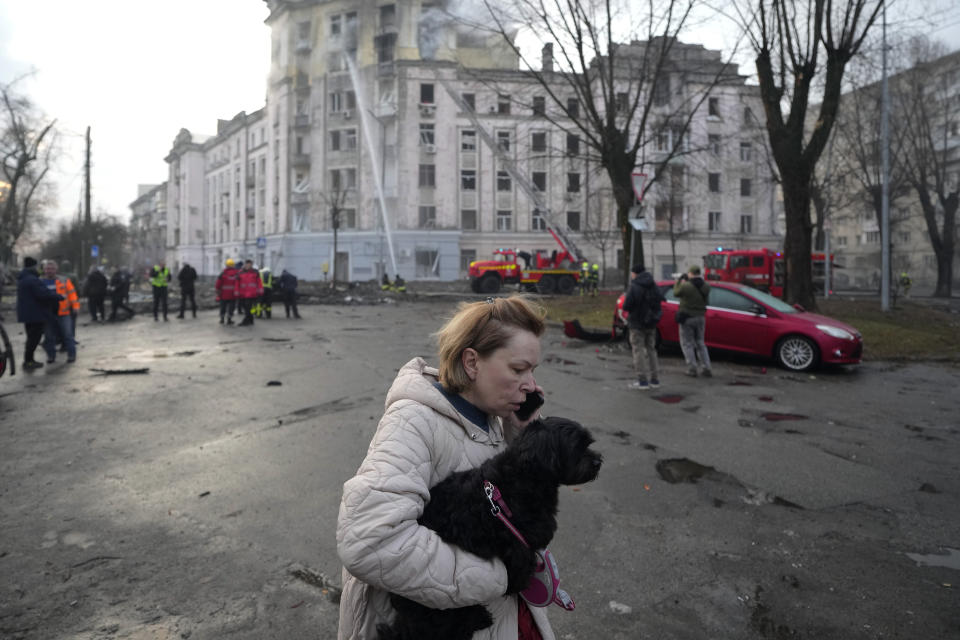 A woman speaks on the phone as she carries her dog near the scene of a Russian attack in Kyiv, Ukraine, Thursday, March 21, 2024. (AP Photo/Vadim Ghirda)