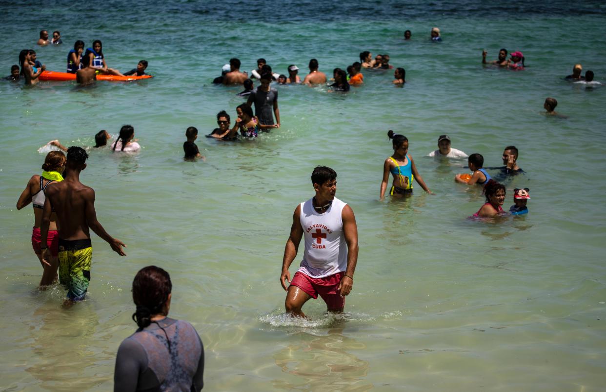 People wade in shallow waters at Playa del Salado in Caimito, Artemisa province, Cuba on Wednesday, July 15, 2020. With government restrictions easing and a heat wave sweeping the island, thousands of Cubans are packing the beaches without masks on the sand and in the water. But after closing down for over three months, COVID-19 infection rates remain extremely low.