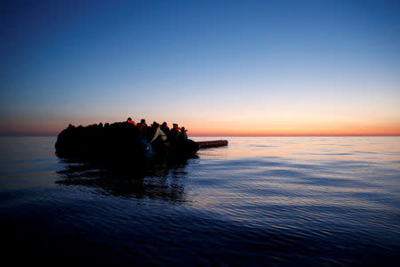 FILE PHOTO: Migrants on a rubber dinghy await rescue by the Malta-based NGO Migrant Offshore Aid Station (MOAS) at dawn in the central Mediterranean in international waters off the coast of Sabratha in Libya, April 15, 2017. REUTERS/Darrin Zammit Lupi/File Photo