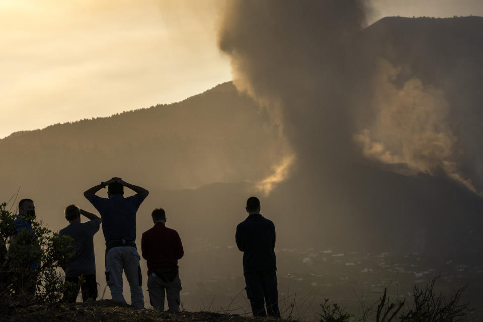 Residents look from a hill as lava continues to flow from an erupted volcano, on the island of La Palma in the Canaries, Spain, Friday, Sept. 24, 2021. A volcano in Spain’s Canary Islands continues to produce explosions and spew out lava, five days after it erupted. Two rivers of lava continue to slide slowly down the hillside of La Palma on Friday. (AP Photo/Emilio Morenatti)