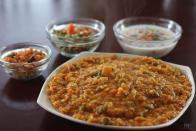 <p>A traditional Karnataka rice preparation, this dish can be relished hot, topped with ghee. Soak 1 cup rice and 3/4 th cup dal (toor dal/arhar dal) separately for half an hour and drain them. Heat some oil in a pressure cooker. Add 2 chopped onion and sauté them. Add 2-3 green chillies, curry leaves and turmeric powder. Add rice and dals with 4-5 cups of water. Bring to a boil. To this add chopped vegetables like drum sticks, potatoes, french beans, capsicum, some chopped tomatoes, asafoetida, red chilli powder, tamarind pulp and salt. Stir well and add bisi bele bhaat masala. Cover and pressure cook till soft. Continue cooking on slow flame for 5 minutes. Stir once it cools down. Some water can be added to loosen the consistency. “Creative Commons Bisi bele bath” by Food and Remedy is licensed under CC BY 3.0 </p>