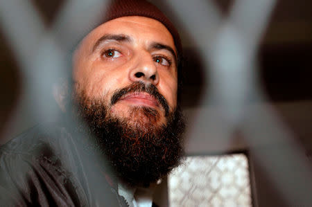 FILE PHOTO: Yemeni Islamic militant Jamal al-Badawi looks from behind bars during the first hearing of a Sana'a court of appeals hearing in Yemen December 8, 2004. REUTERS/Khaled Abdullah/File Photo