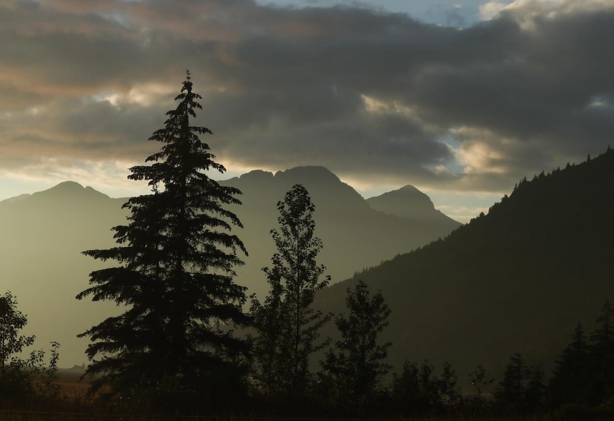 Trees are silhouetted against the backdrop of a mountain range along the Seward Highway as the sun sets outside of Anchorage, Alaska, on Aug. 23, 2023.
