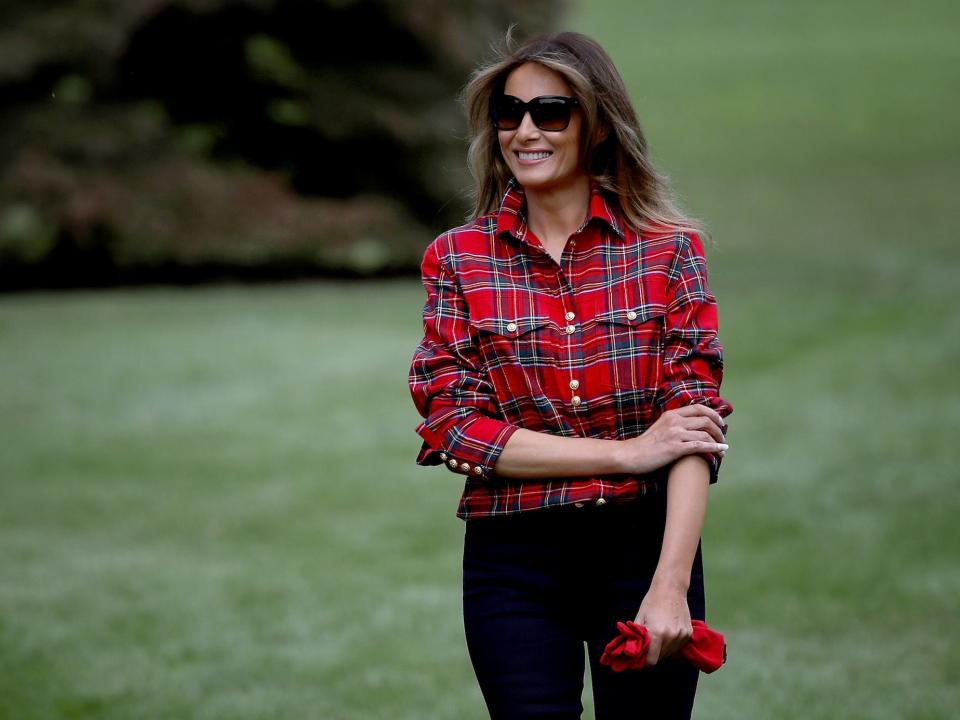Melania Trump, wearing a red plaid shirt, arrives for an event in the White House Kitchen Garden on the South Lawn of the White House in 2017.